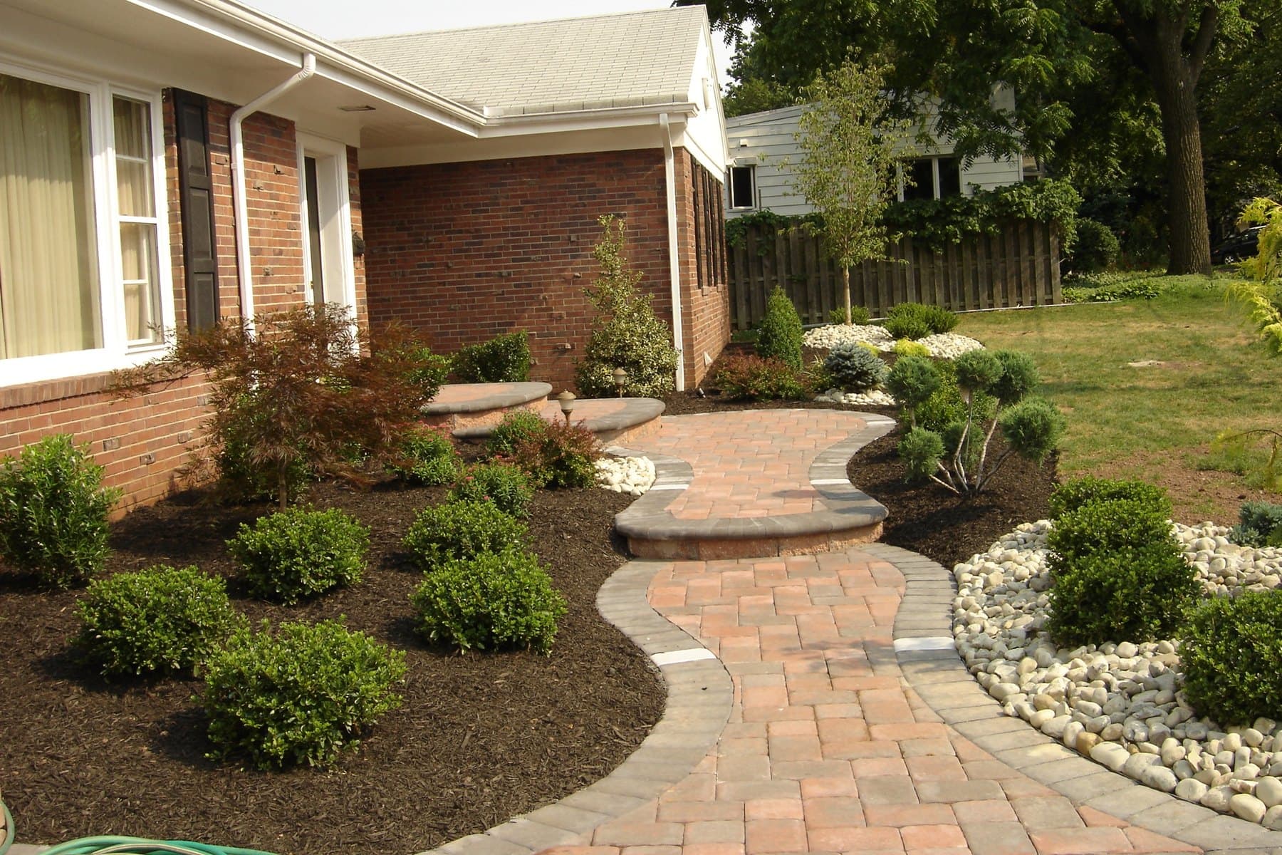 Curved paver walkway with mulched beds and specimen trees