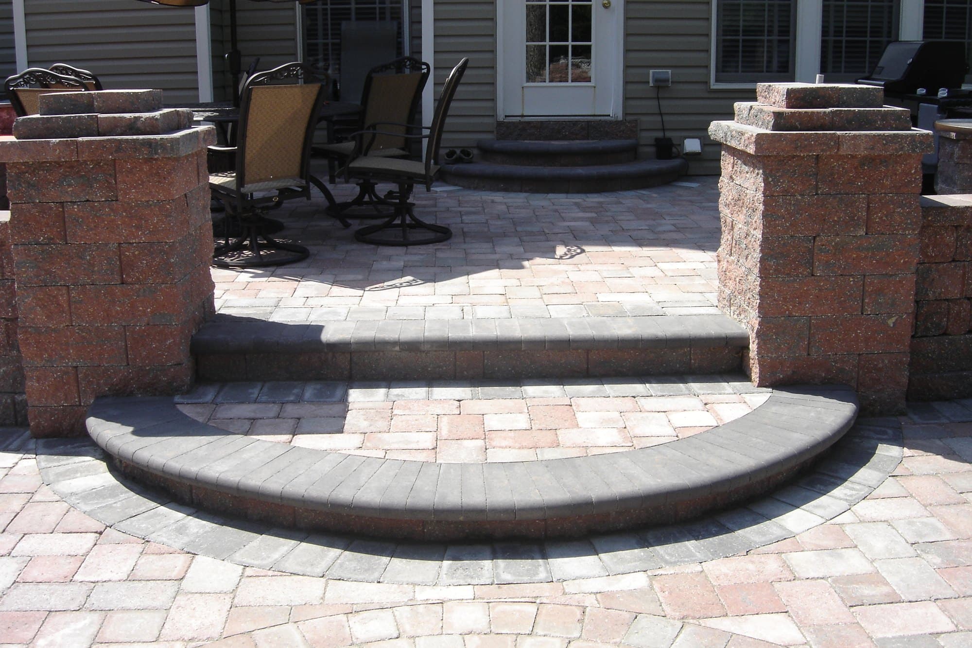 Multi-level paver patio with stone pillars and curved steps