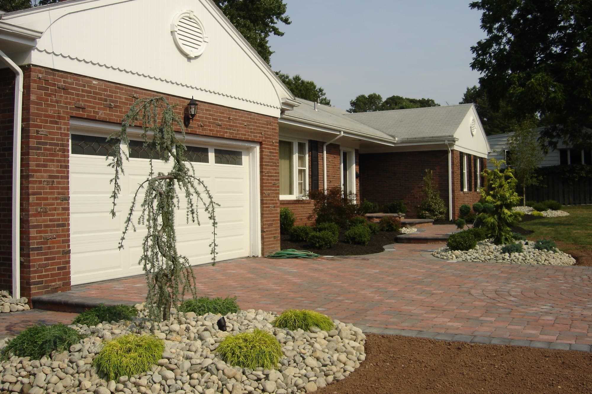 Paver driveway, river-rock beds, and foundation plantings